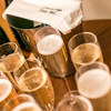 Full champagne flutes on a table with an ice bucket, covered with a cloth, in the background