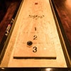 Close up of a shuffle board table with a puck in between the numbers two and three