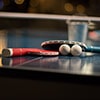 Two ping pong bats balancing on a ball, on a table