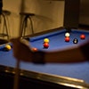 Through the arm shot of pool balls spread out on a table