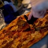 A hand cutting a pizza