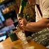 A man pouring a shot of Jameson Whiskey into a glass, over ice