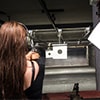 The back of a woman firing a pistol at a target, in a shooting range