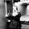 Black and white image of a woman pointing a gun at the camera