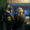 A girl being shown how to fire a gun by an instructor