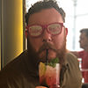 A man wearing Team Bride glasses and sucking a cocktail from a straw