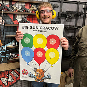 A man with ear protectors holds up a sign promoting a shooting range