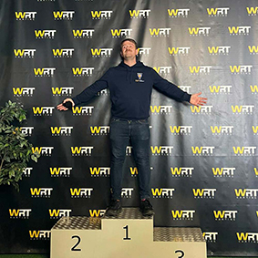  A man celebrates on a podium having finished first during go-karting