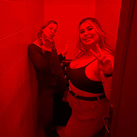  Two women pose for a picture inside a red-coloured room