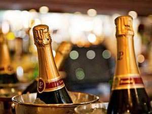 A row of metal ice buckets filled with ice and bottles of champagne