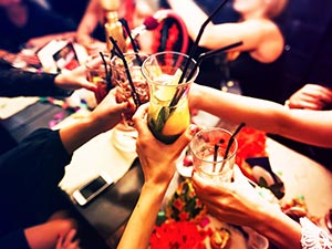 People clinking their cocktail glasses together in a cheers position