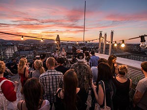 Some people on a rooftop terrace watching the sunset
