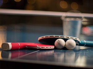 Two ping pong bats along with a ball, set up on a table
