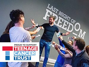 People waving ten pound notes at a man with his hands in the air in front of a Last Night of Freedom logo