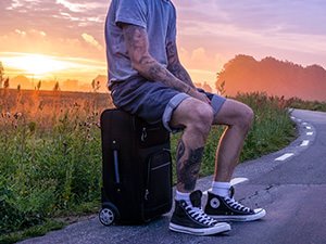 A man sitting on a suitcase in the middle of nowhere