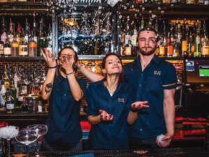 Three bartenders behind a bar