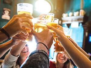 A close up of a group of people cheering, with pints
