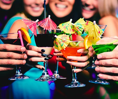 Some girls holding their martini glasses in front of them, with tiny umbrellas in