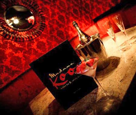 A reserved table at Madame Koo, topped with champagne and a cocktail