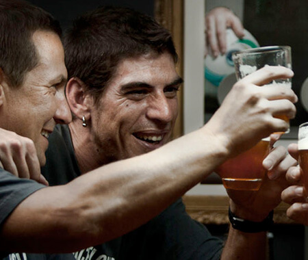 A group of men holding up beers in a pub in Barcelona