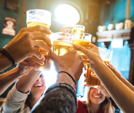 A close up of a group of people cheering, with pints