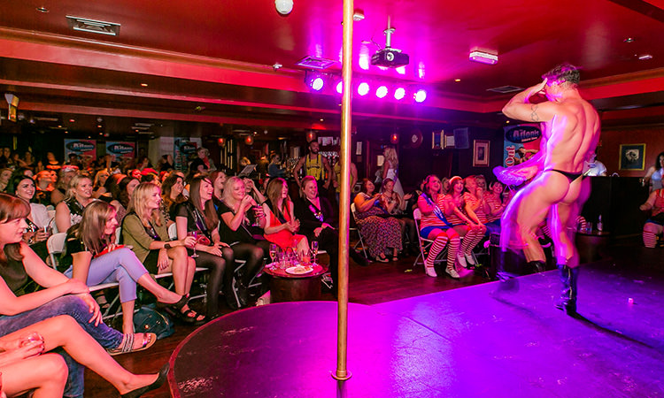 A man stripping to an audience of women