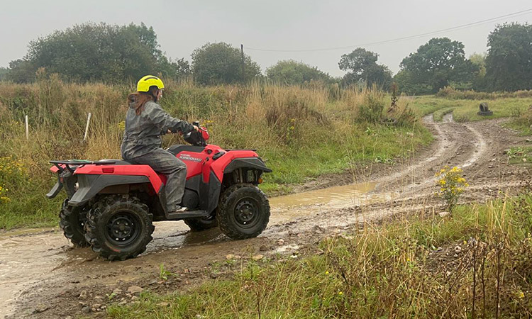 A women driving a quad bike over a puddle at Max Events in Bristol. 