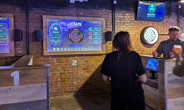 A woman standing in from of a darts board at Boom Battle Bar