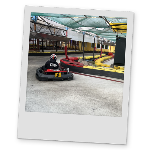 A polaroid style image of a person driving a go kart wearing an LNOF hoodie
