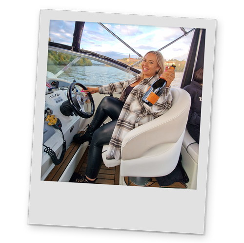 A polaroid style image of one of Team LNOF driving the boat and holding a bottle of prosecco