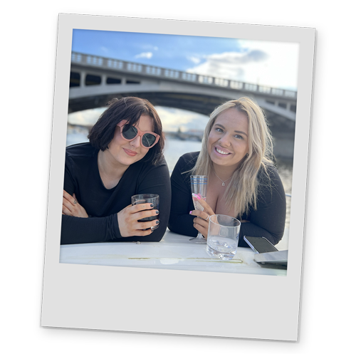 A polaroid style image of two of Team LNOF holding glasses and smiling on the river cruise