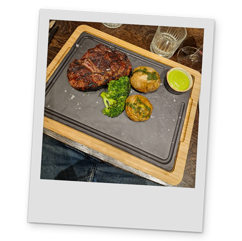 A polaroid style image of a plate of steak, potatoes and broccoli