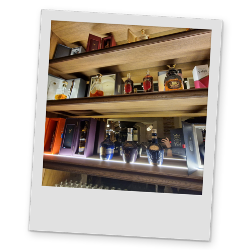 A polaroid style image of a shelf of expensive liquors