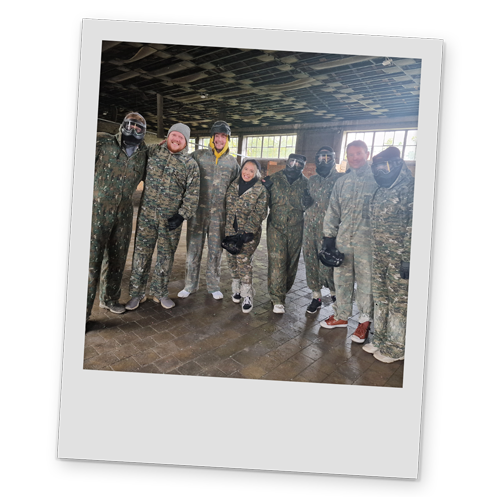 A polaroid style image of Team LNOF in camo overalls at paintballing