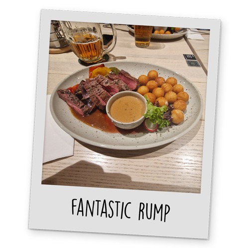 A polaroid style image of a plate of steak, potatoes vegetables and gravy, with text reading 'Fantastic Rump' at the bottom