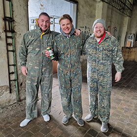  Three men wearing camo overalls posing for the camera