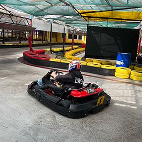 A person driving a go kart with an LNOF hoodie on