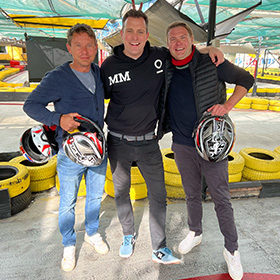 Three men holding helmets at go karting