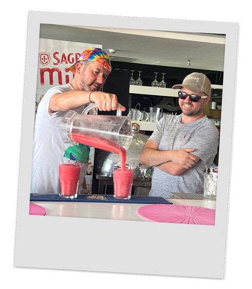 Two male members of our team pouring out their red coloured cocktail 