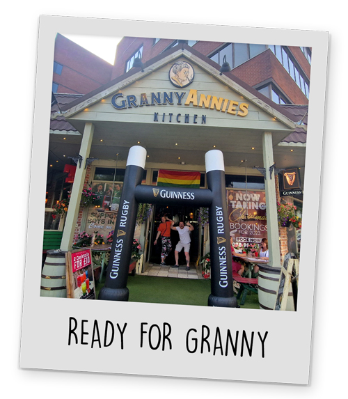The outside of Granny Annies kitchen with an inflatable archway that says 'Guinness' and two members of our staff posing in the doorway