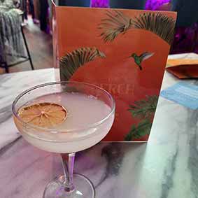  A cloudy looking cocktail with The Perch menu just behind it 