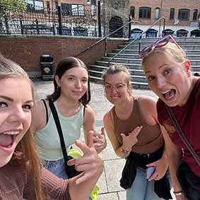  Four female members of our team in Belfast city centre doing finger guns 