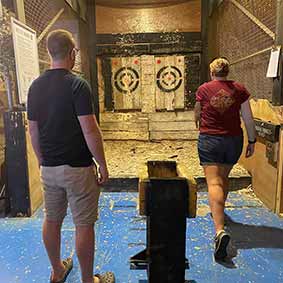  A male and a female member of our staff after they have just thrown axes as the two targets in front of them 