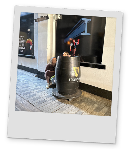 Two female members of our staff hiding behind a Guinness barrel