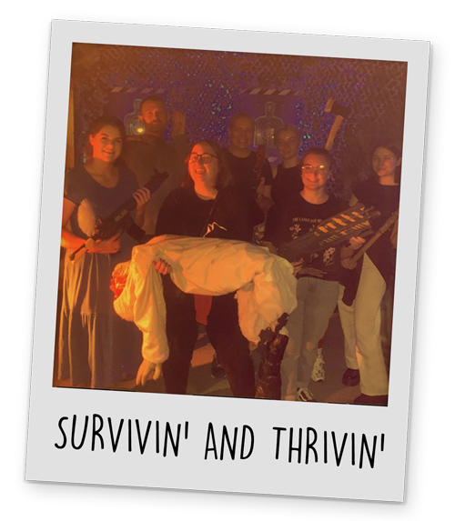 Team LNOF posing in the zombie themed escape room with a fake body and axes with the caption 'survivors'.