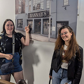 Hannah S and Hannah L posing with a piece of art that reads Hannah's 