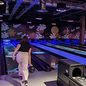 Zoe holding a bowling ball about to roll it at the pins 