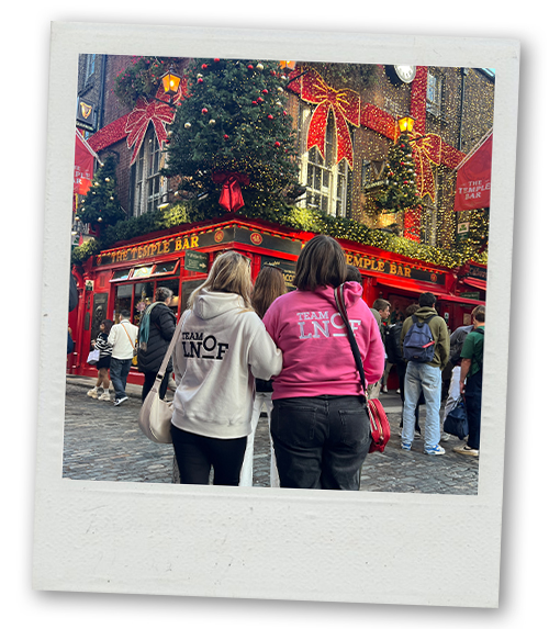 A back view of Billie and Hannah wearing their LNOF hoodies and facing Temple Bar