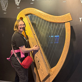 Hannah posing next to a massive harp at the Guinness Factory Tour 
