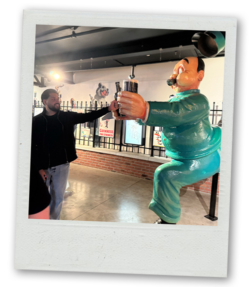 Akash doing a fist bump with a statue of a cartoon at the Guinness Factory Tour